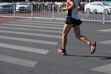 Fototapeta premium Legs of marathon runner running on city road