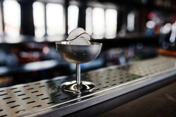Alcoholic cocktail with ice and coconut in silver glass on bar table.