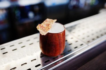 Alcoholic cocktail in wooden cup at  bar table.