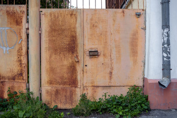 A rusty gate of an old house with an electronic lock