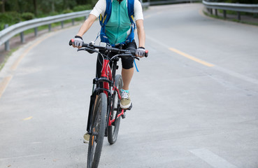 Fototapeta na wymiar Woman cyclist riding mountain bike on road