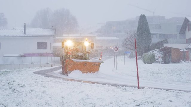 Snow Plow Tractor Clearing Road During Snowstorm