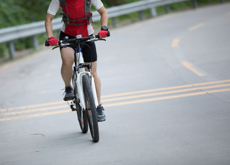 Naklejka na ściany i meble Woman cyclist riding mountain bike on road