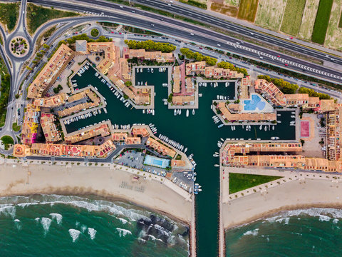 View from the air to the entrance to Port Saplaya Bay and agrarian fields around during a bright sunset. Valencia