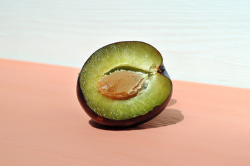 Half plum with a stone on a pink table