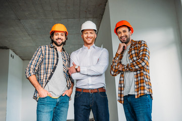 group of smiling architects inside of constructing building looking at camera