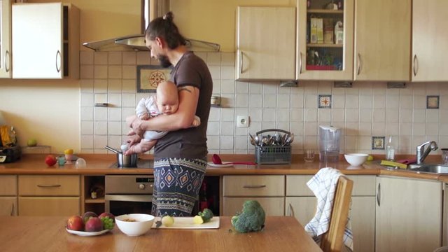 A lonely young father warms up baby food in a bottle for his son. Feeding the baby. Father's Day, conscious paternity