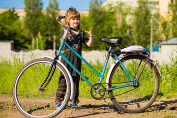 Fototapeta na wymiar Happy little girl riding big bicycle in city park