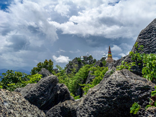 Temple in clouds with pagodas perched high on top of a rocky hill, Wat Chalerm Prakiat temple in...