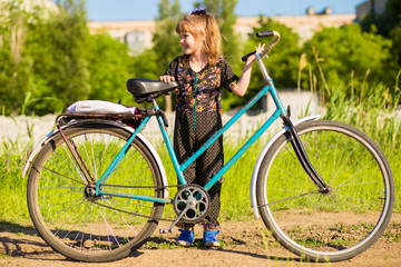 Fototapeta premium Happy little girl riding big bicycle in city park