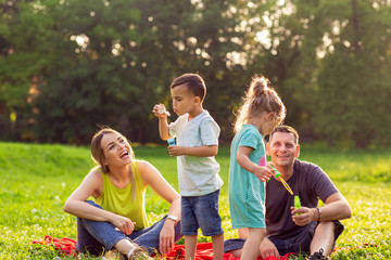 Happy male and female playing with children outside.