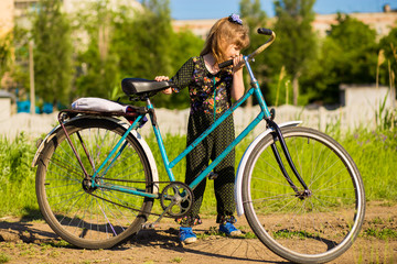 Fototapeta premium Happy little girl riding big bicycle in city park