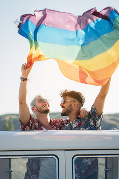 Gay couple in van holding LGBT flag