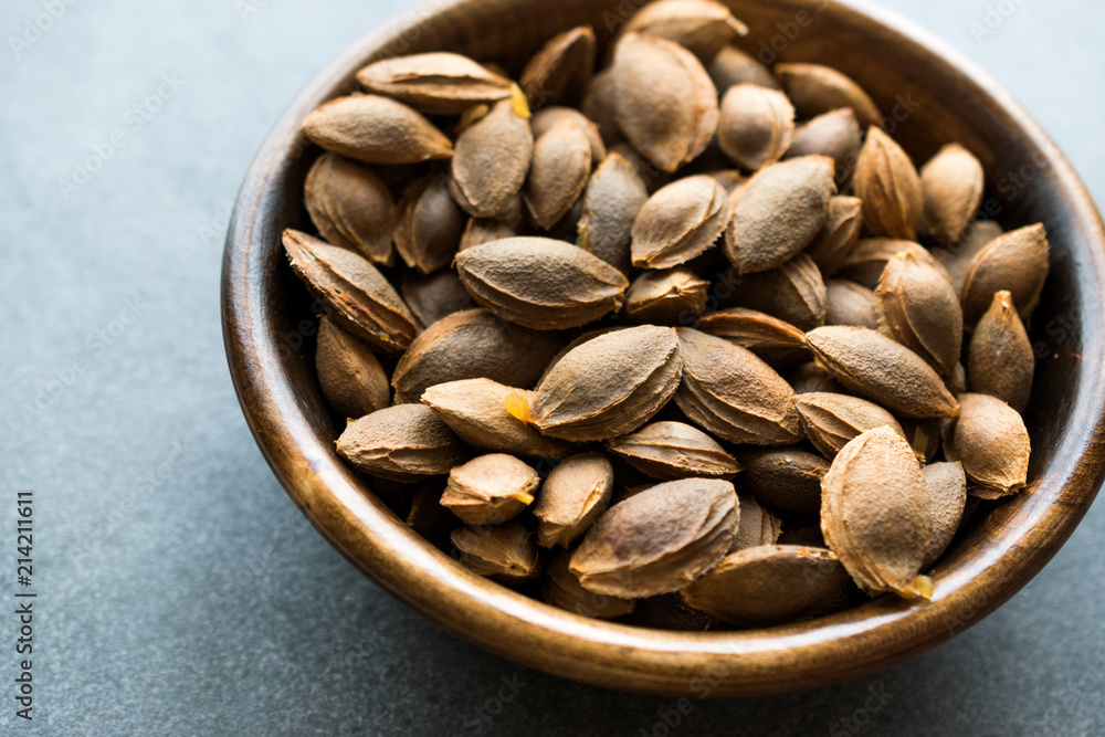 Wall mural dried apricot kernels in wooden bowl.