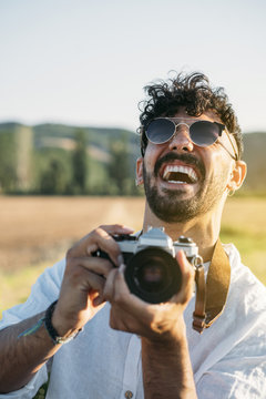 Cheerful man with photo camera in nature