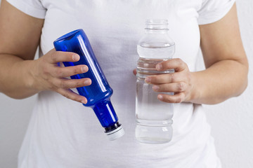 A person holding glass and plastic bottles