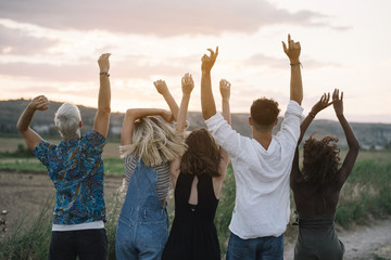 Cheerful friends dancing and jumping in nature