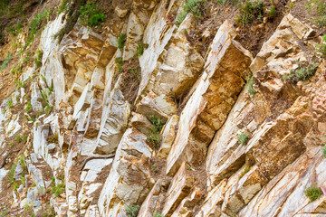 Brown stone texture. Rock formation with cracks and protrusions. Mountain of castle San Juan. Spanish beach resort Blanes in summertime, Costa Brava, Catalonia, Spain