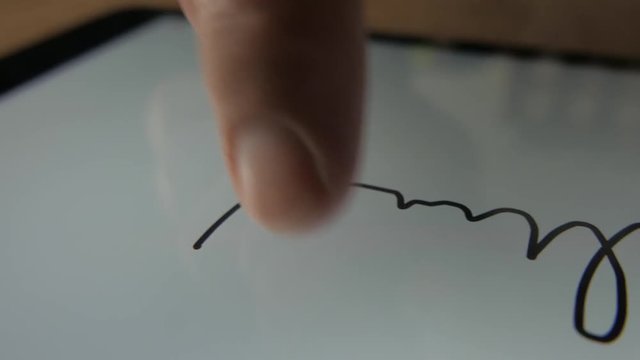 E-signature. Man is writing his signature directly on tablet with finger.
