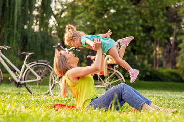 family, happiness, childhood and people concept - Young mother raising her girl child up.