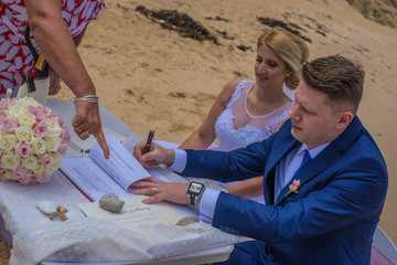 Just married couple signing marriage certificate at beautiful Australian beach.