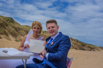 Fototapeta premium Just married couple holding certificate at beautiful Australian beach.