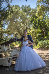 Fototapeta premium Just married couple wearing wedding dresses standing beside vintage cannon. Shot at wedding in Australia on amazing sand beach.
