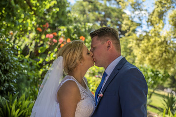Just married couple wearing wedding dresses kissing in beautiful green garden. Shot at wedding in Australia on amazing sand beach.