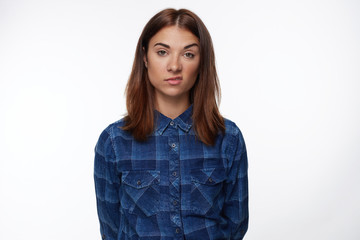 Unhappy beautiful brunette young female frowns face in displeasure, looks directly into camera,...