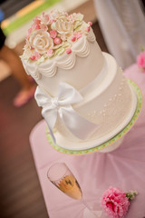 White wedding cake with beautiful ornaments in shape of roses. Shot at wedding in Australia on amazing sand beach.
