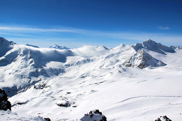 Fototapeta na wymiar Snowy Mountains in the clouds blue sky Caucasus Elbrus