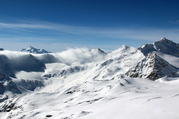 Fototapeta na wymiar Snowy Mountains in the clouds blue sky Caucasus Elbrus