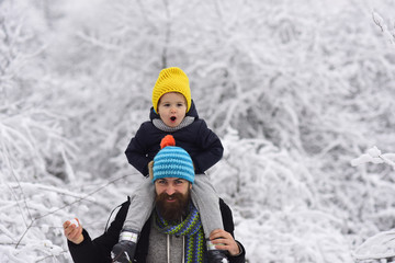 Fototapeta na wymiar Small child, little boy sits on dad shoulders and smiling, laughing, playing, having fun outside. Three year old boy walks with father on winter frosty day. Bright emotions, happy family concept