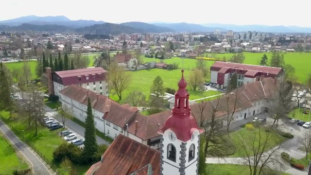 There is a church and a cemetery and they are situated on the edge of a town. Aerial shot. Landscape is beautiful and green at this time of year.