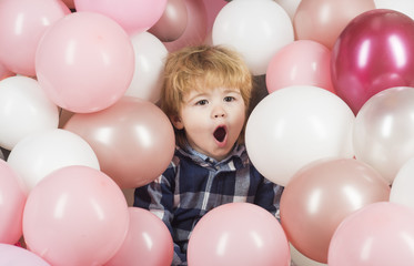 Fototapeta na wymiar A sweet child is singing or screaming. A beautiful baby face between balloons. Holiday and entertainment. Children's weekend, enjoying life. Song or scream, whim, upbringing, emotions on child's face