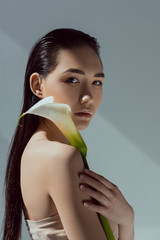 attractive asian woman with calla flower, isolated on grey