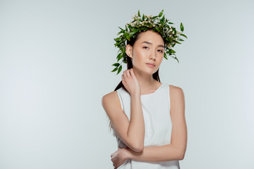 beautiful asian girl posing in floral wreath, isolated on grey