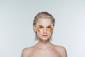 nude woman with golden eye patches, isolated on grey