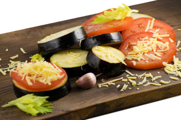 Summer food: sliced eggplant and tomato. Tomatoes, aubergines, cheeses, garlic and celery on a wooden board.