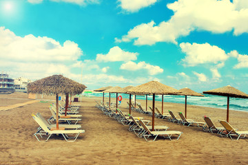 Straw umbrellas and chaise lounges on the southern tropical beach