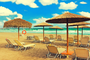 Straw umbrellas and chaise lounges on the southern tropical beach