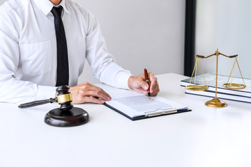 Businessman or lawyer working on a documents, judge gavel with Justice lawyers at law firm in background, Legal law, advice and justice concept