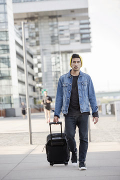 Germany, Cologne, portrait of young man pulling trolley