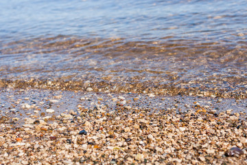 Finely pebble seaside and clear sea water. Sea surf.