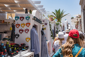 Tourists walk through small shops in the Oia village on the Thira island, Greece. - obrazy, fototapety, plakaty