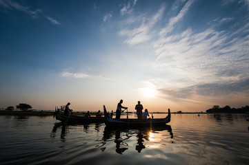 Naklejka na ściany i meble Boats with tourists on the Taung Tha Man Lake with the U Bein Bridge in the background during a sunset in Mandalay, Myanmar