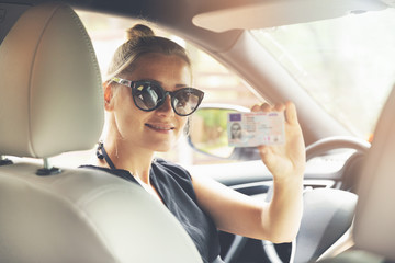 woman showing her new driver license in a car