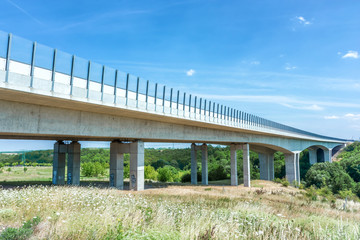 Fototapeta na wymiar Lange Autobahnbrücke führt über grünes Tal