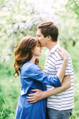 Obraz premium Close up portrait of lovely future parents during sunset on nature apple tree background