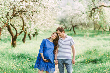 Fototapeta premium Close up portrait of lovely future parents during sunset on nature apple tree background